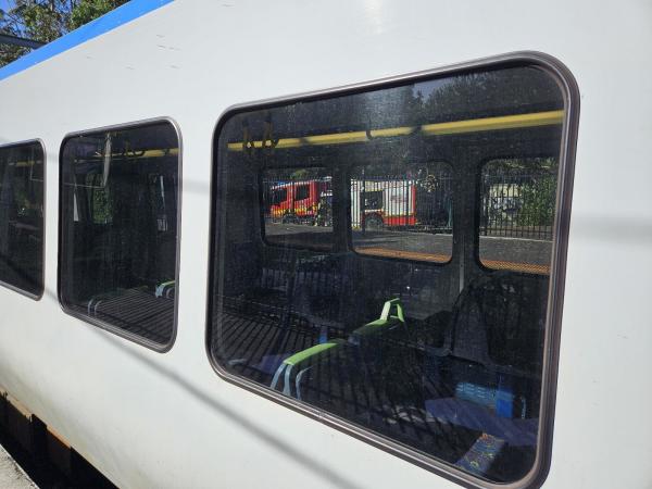 A train stopped at a suburban train station. Through the window you can see a fire truck, attending to something out of sight.